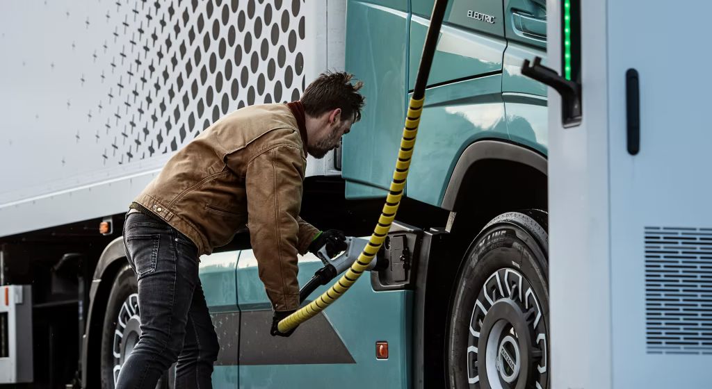 A man charging a Volvo truck.